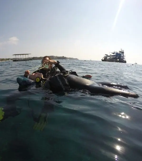 Scuba instructor assisting a floating diver with regulator during a surface rescue near Nusa Penida